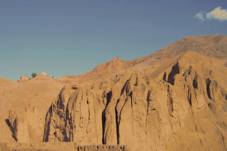 two sheep are grazing in the dirt by mountains