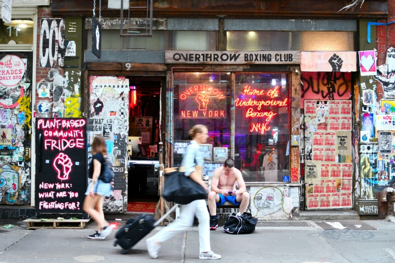 people with luggage walking on street in front of store