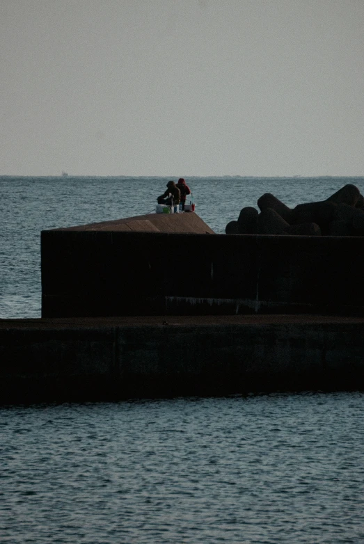 two people sitting on the roof of a concrete structure