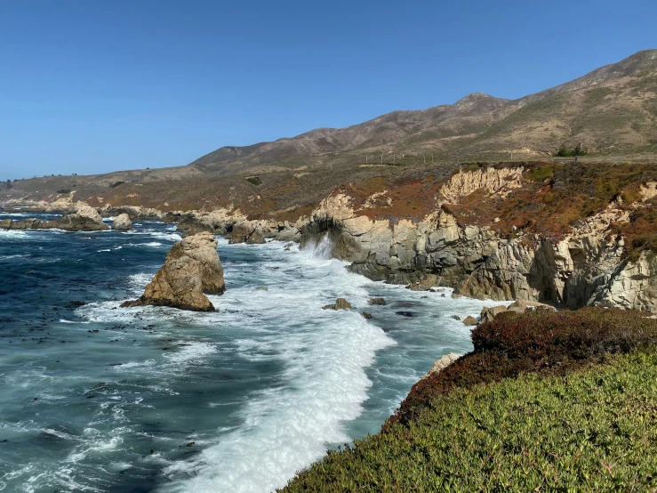 the cliffs near the ocean have waves coming up