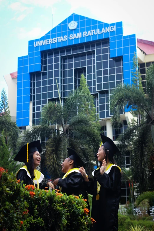 three people in their graduation gowns posing outside of a building