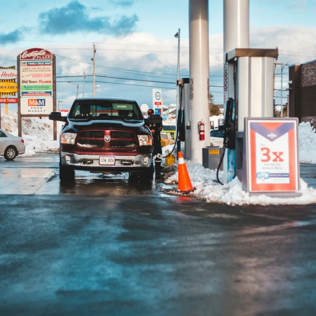 a truck sitting in the middle of a gas station with an orange cone