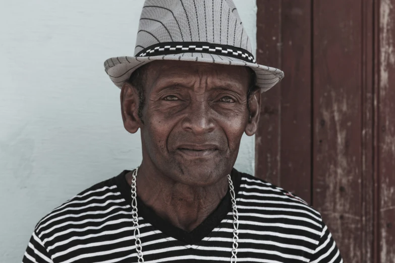 man wearing a hat and a necklace with a black and white striped shirt