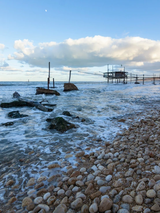 a beach that has many rocks in the water and there are boats on it