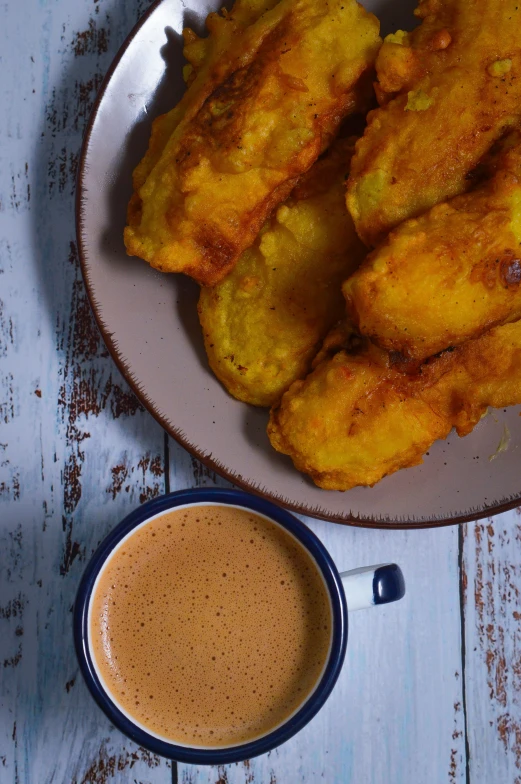 fried food is served on a plate next to a cup of coffee