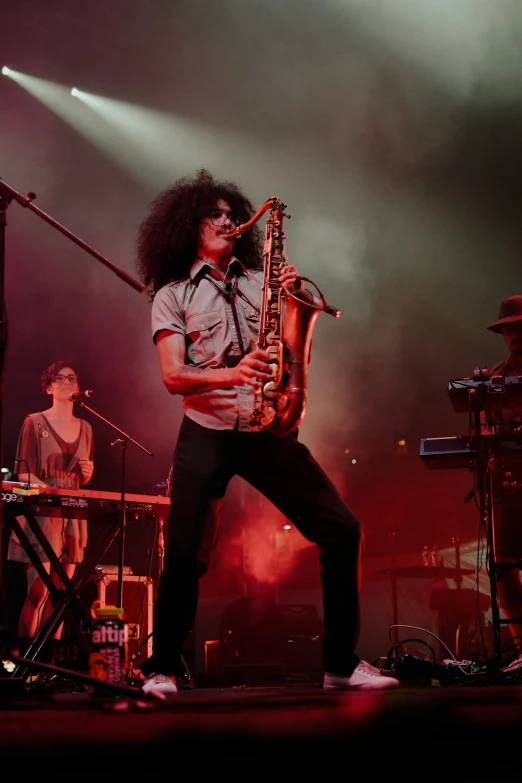 man standing on stage while holding a saxophone