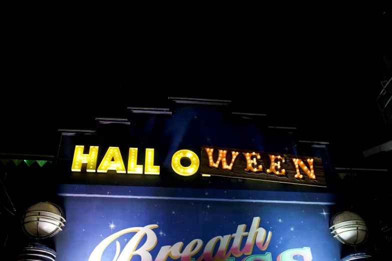 a sign at halloween is lit with yellow and green