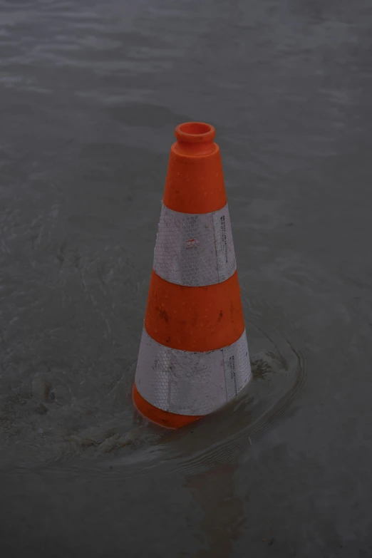 an orange and white cone is in the water