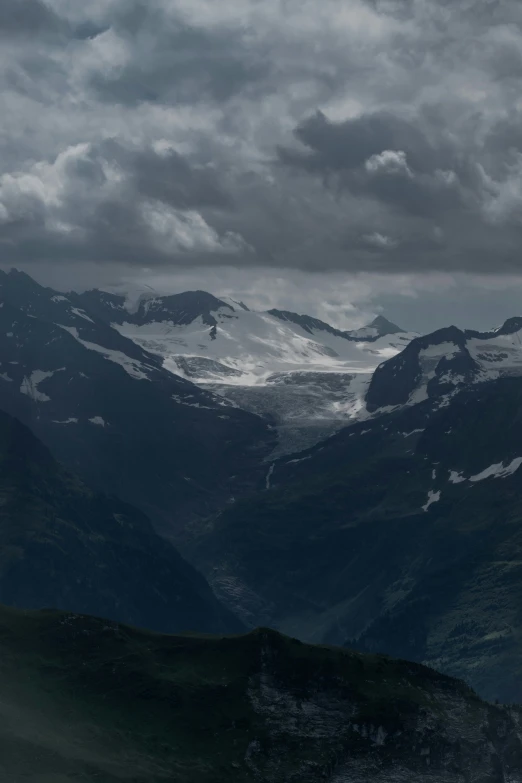 the mountain landscape with snow is covered by dark clouds