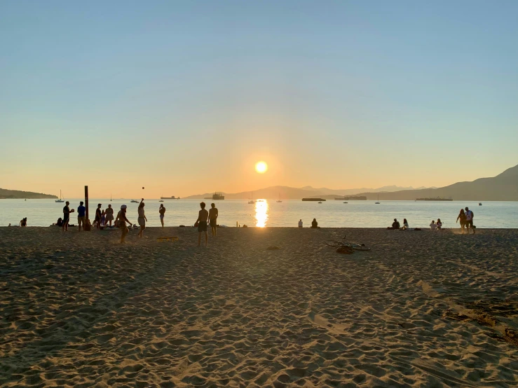 some people stand on a beach by the water