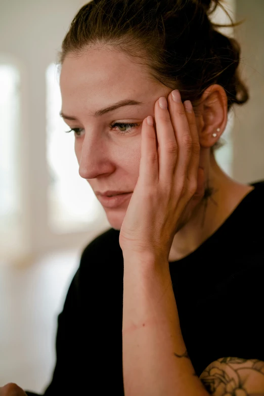 a woman has her hand on the face of her ear