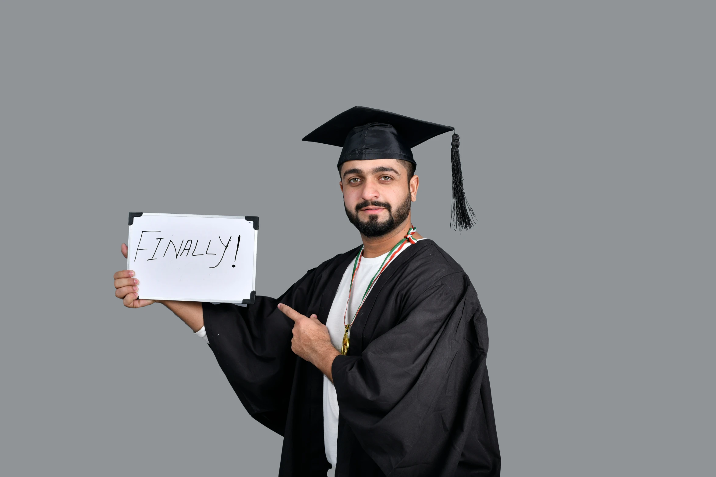 a male student in a black cap and gown is holding his diploma