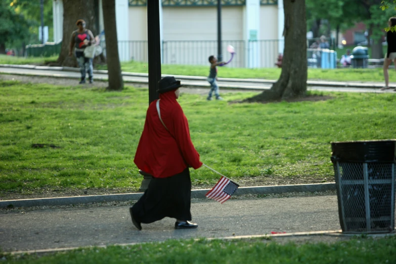 a woman walking across a park holding a flag