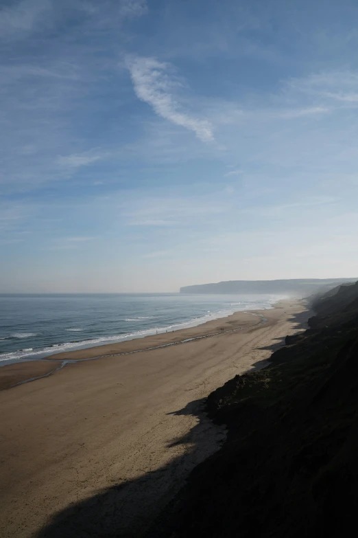 two people are walking down the sand toward the ocean