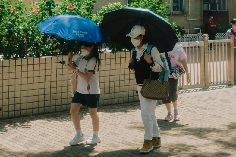 two girls are standing under umbrellas in the shade