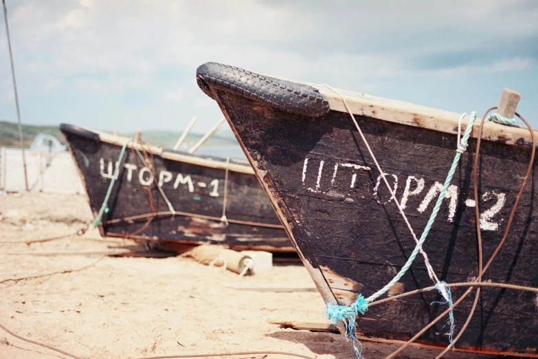 two small boats with writing on them sit in the sand