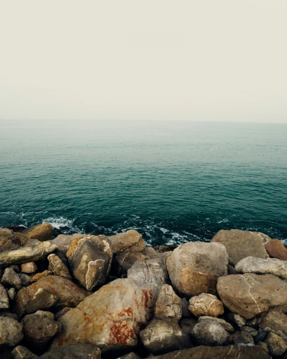 some rocks water and blue sky on a hazy day