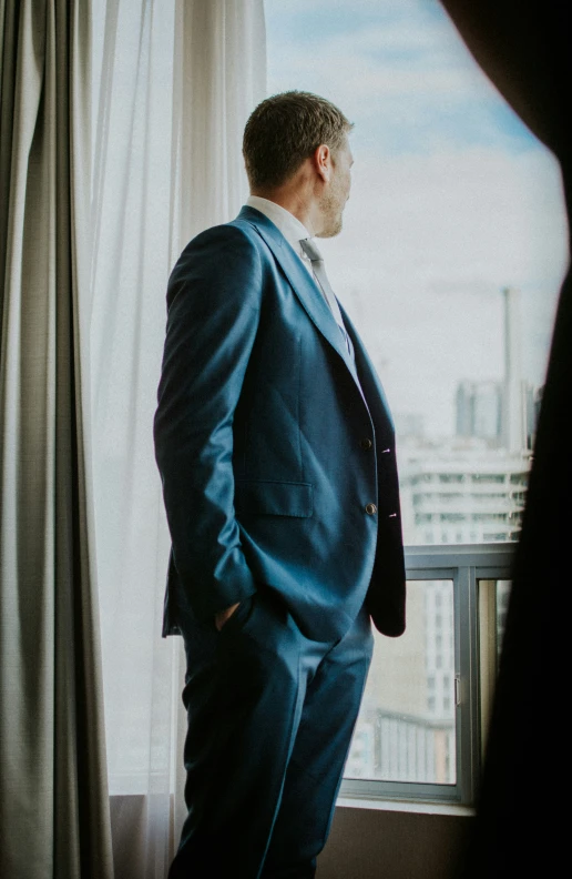 a man looks at the window and his suit