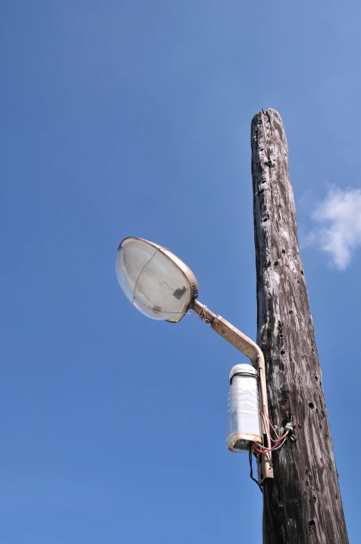 an electronic streetlight on a wooden pole under a blue sky