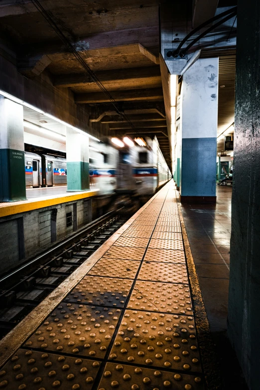 an empty subway station platform is lit by a moving train