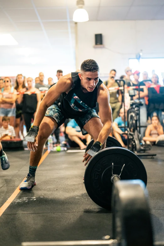 a man lifting a barbell in front of a crowd