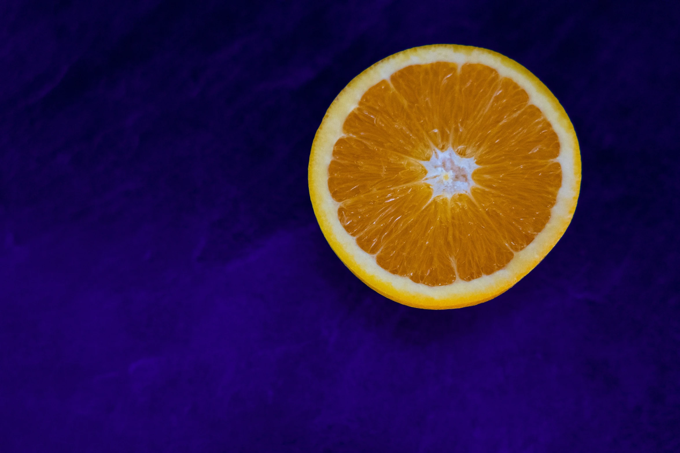 a half of an orange with a white center on a purple background