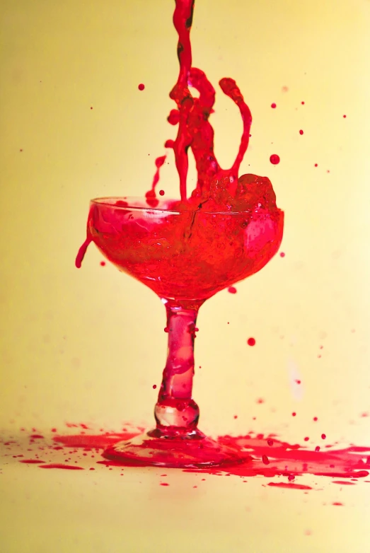liquid being poured into a wine glass with a red substance floating on top