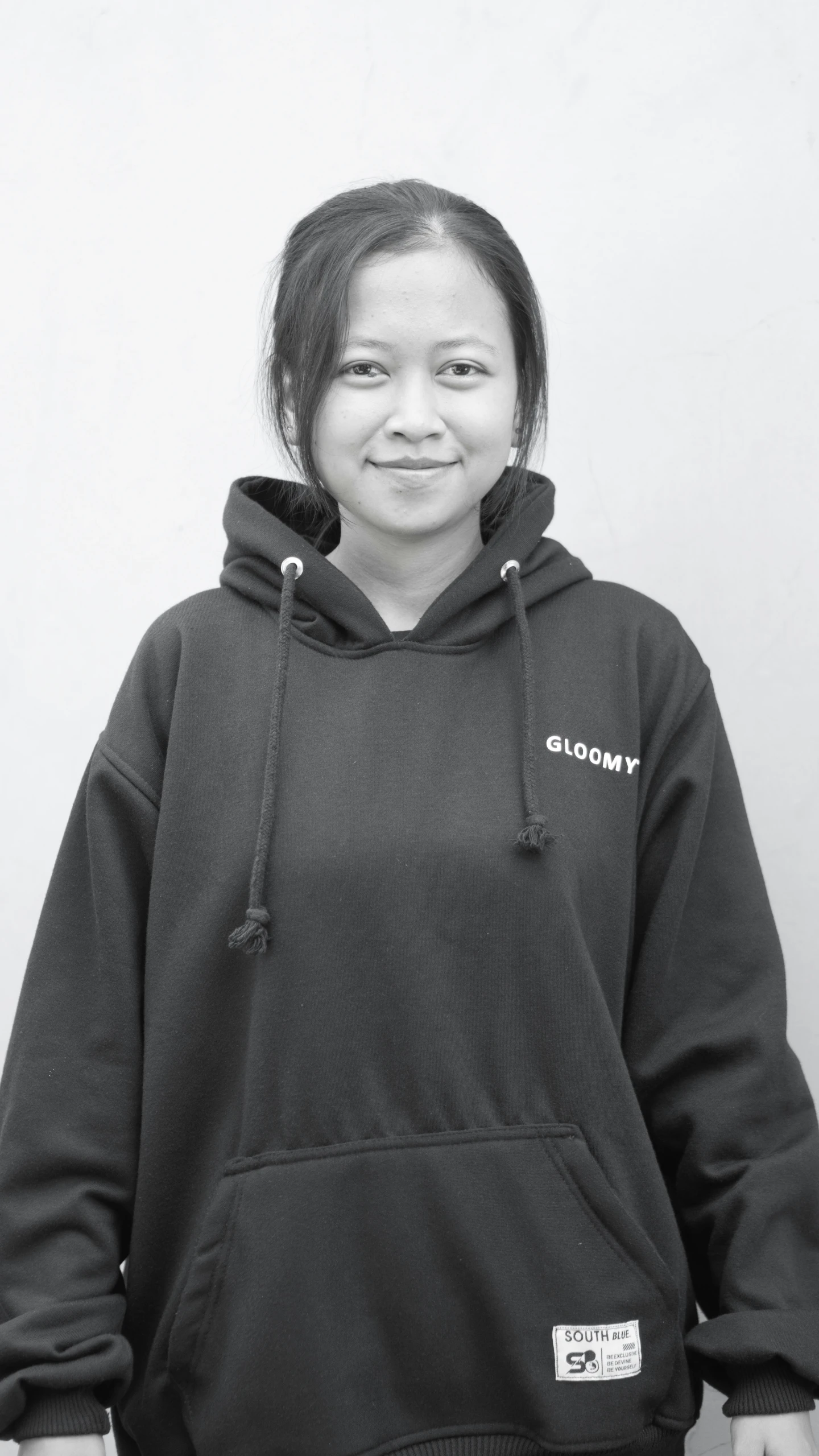 the woman is standing in front of a white wall wearing a black sweatshirt