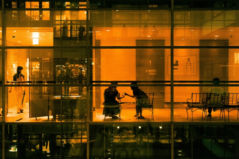 several people are walking inside a window lit at night