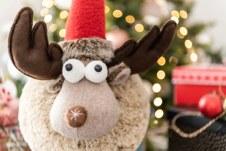 a stuffed moose toy with a red nose is on top of a christmas tree