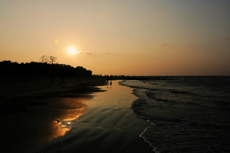 the sun is setting over the water at the beach