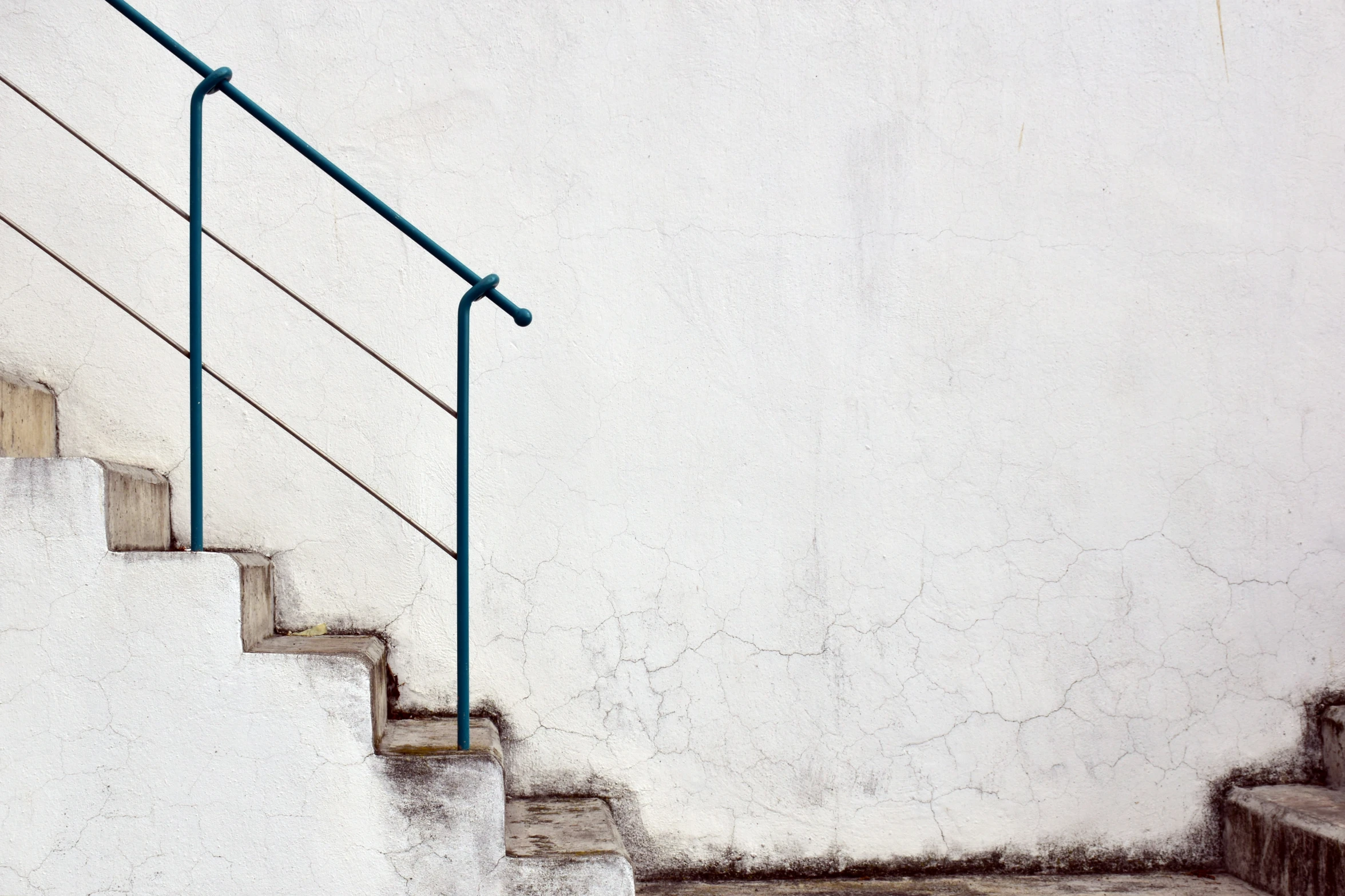 a metal hand rail next to some concrete stairs