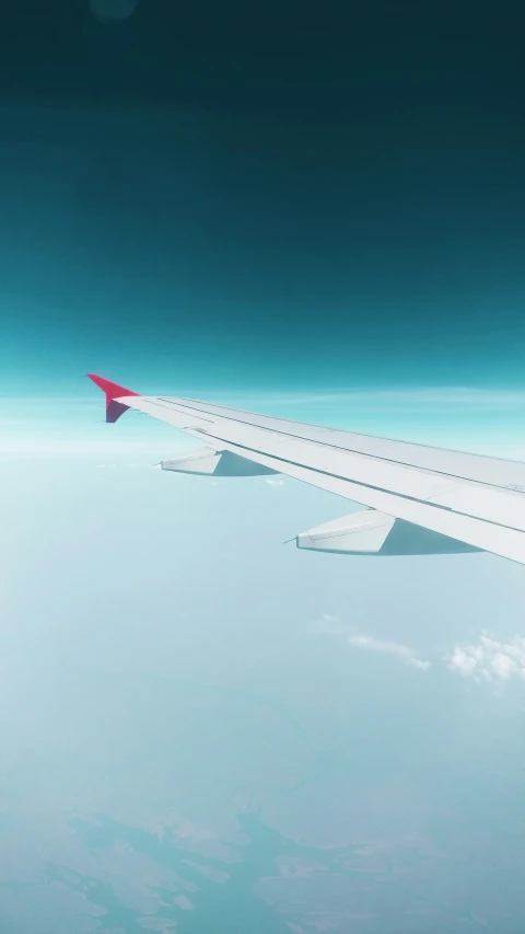 view from an airplane window looking down at clouds and wing