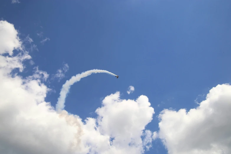 a white feather flying through a blue cloudy sky