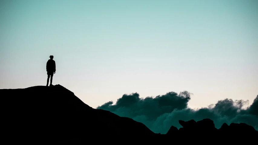 man on top of hill staring into sky with cloud