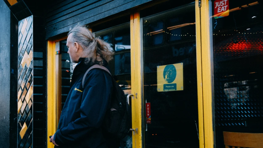 woman with back pack walks outside doorway of building