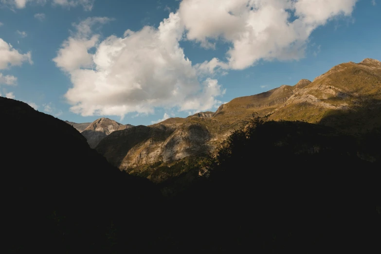 clouds move in over the mountains in front of some trees