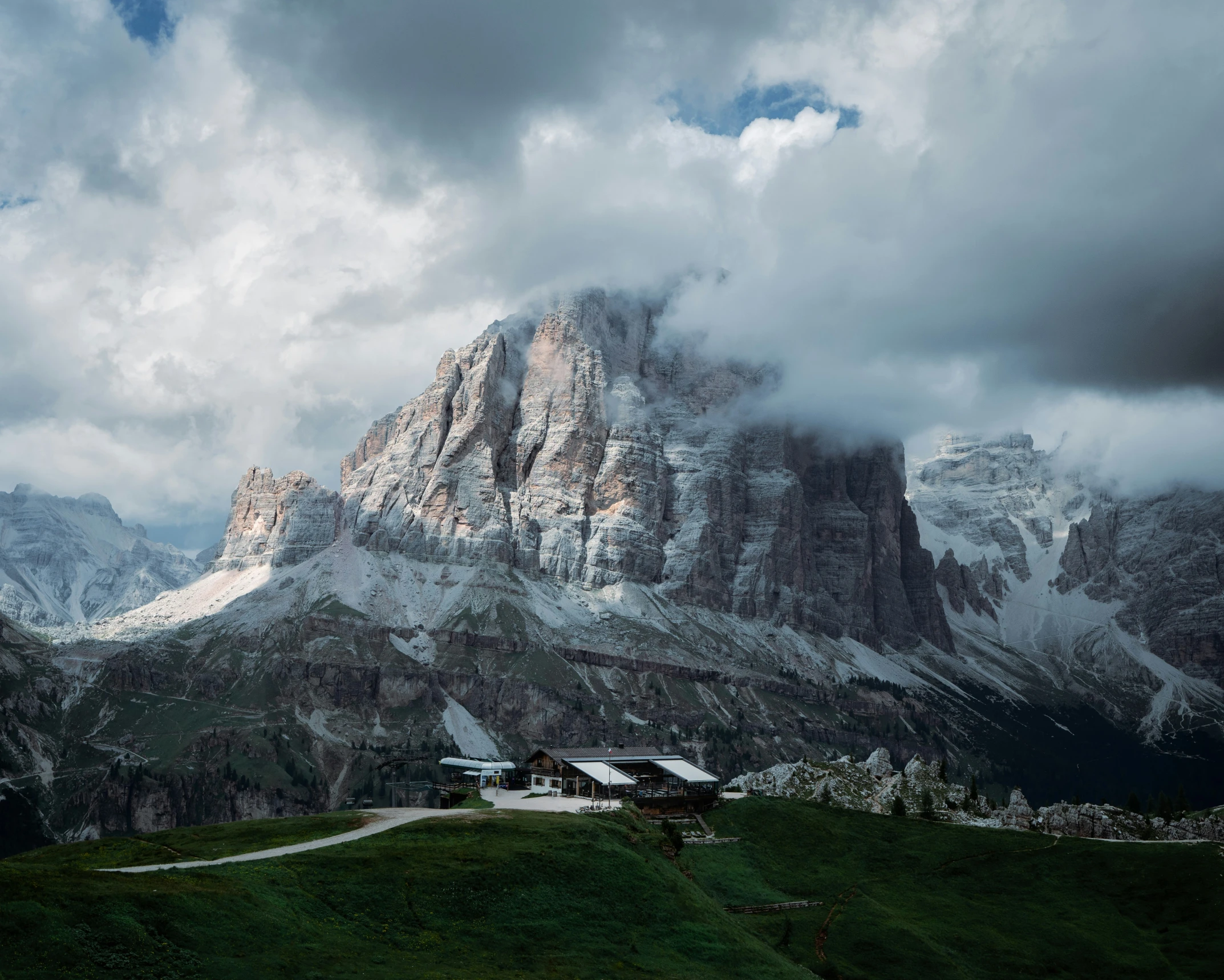 a mountain view has clouds over it and houses on the hill