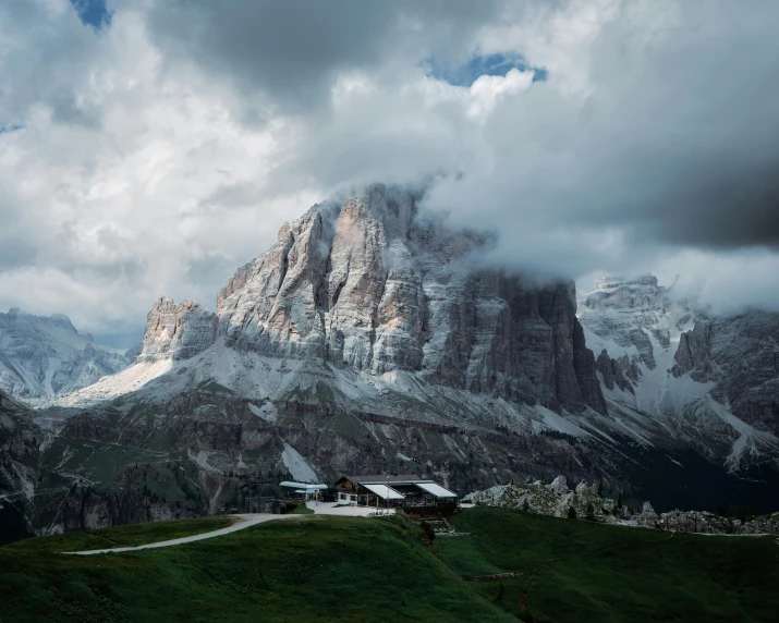 a mountain view has clouds over it and houses on the hill