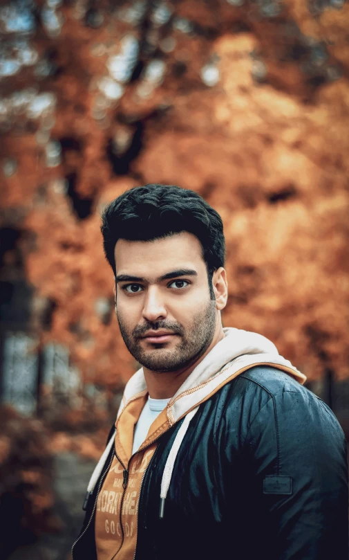 man looking into the camera while standing in front of leaves