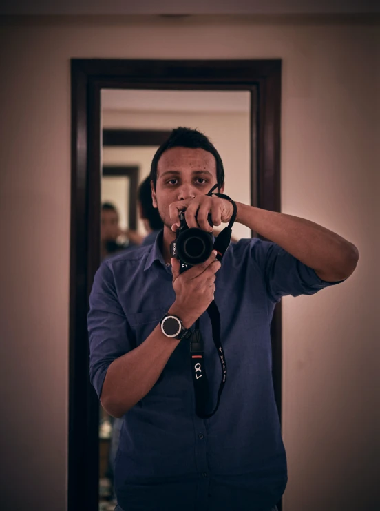 a man holding a camera taking a po in the mirror