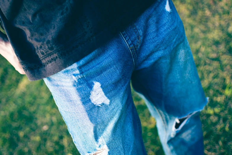 a person with torn jeans standing in a field