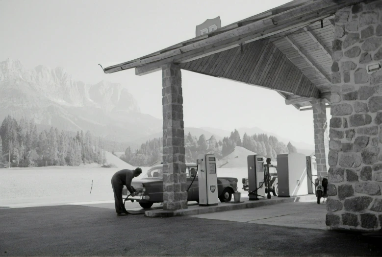 a man is pumping gasoline into his old fashioned car