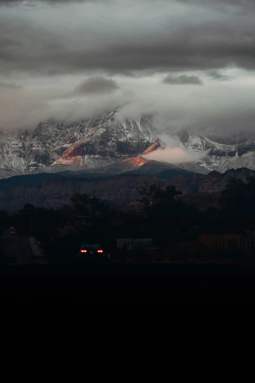 snow capped mountains rise over a city under cloudy skies