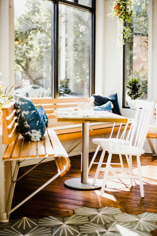 a wooden table with three white chairs and two windows