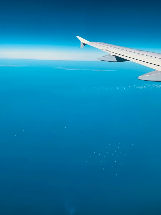 an airplane wing is shown above the blue water