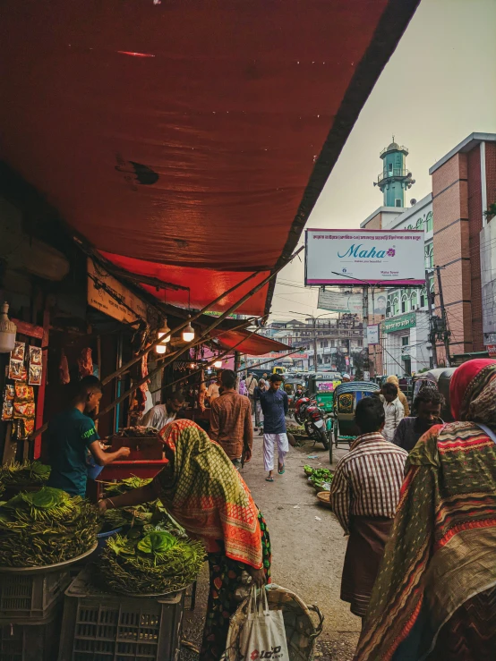 a bunch of people walking down an open air market