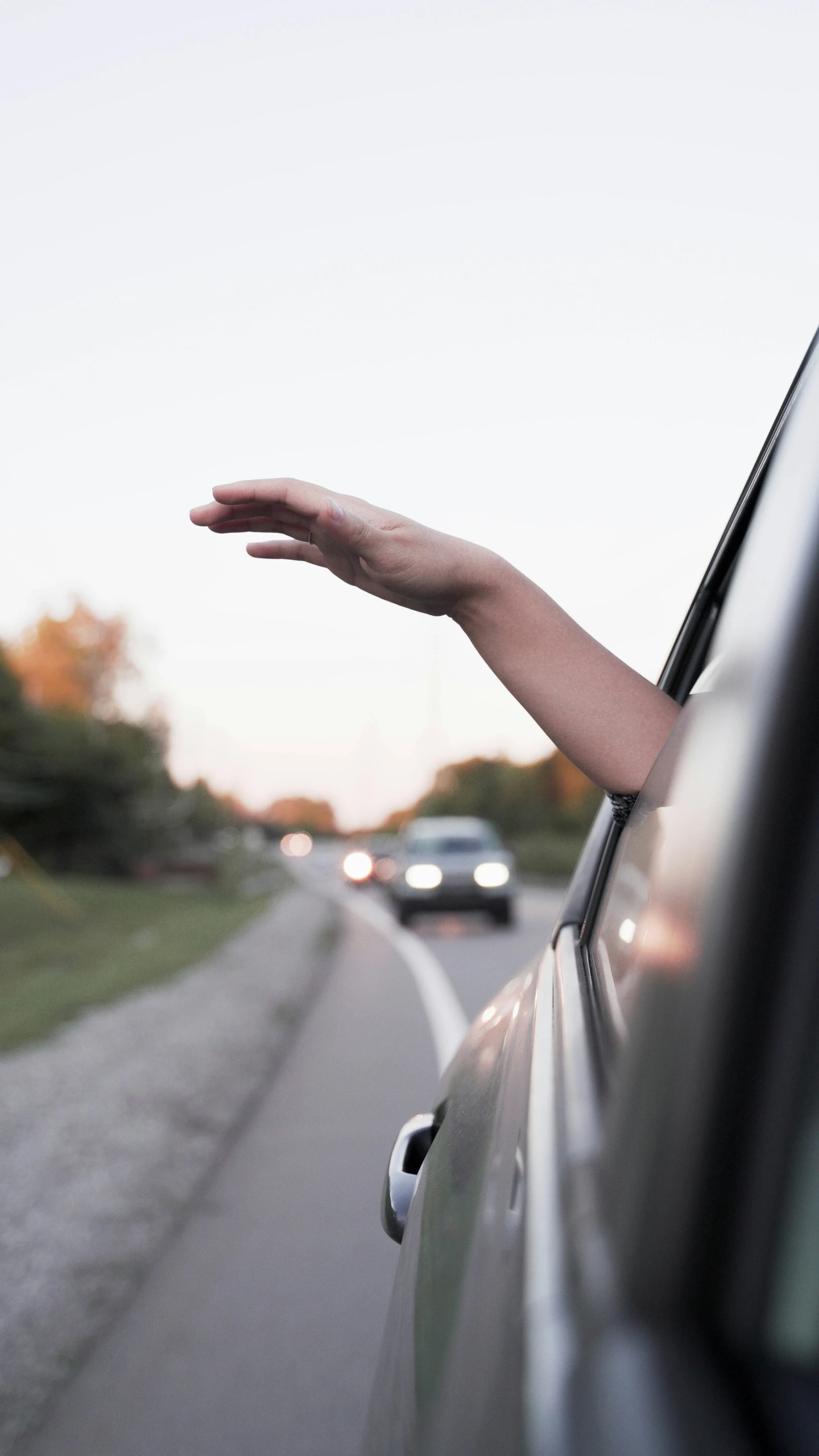 a hand sticking out the window of a car