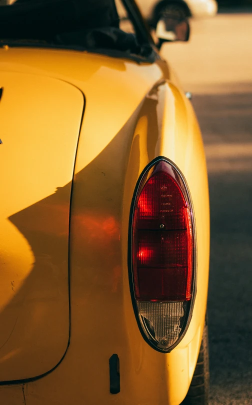 the back end of a yellow car with its hood down