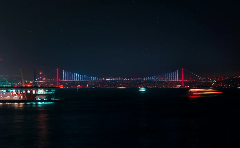 the city skyline and lights are lit up as a boat sails near the bay